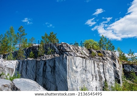 Large grey stones in an old abandoned quarry. Marble texture. Smooth cuts on the rocks. The marble quarry is horizontal. The natural stone. Marble quarry, marble rocks in the wild.