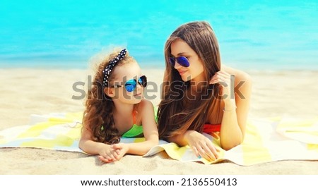 Summer vacation portrait mother and child lying together on beach, background of sea