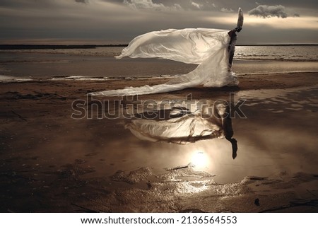 Girl in a long dress made of film on a dried lake, beautiful landscape, the image of a woman with Venus