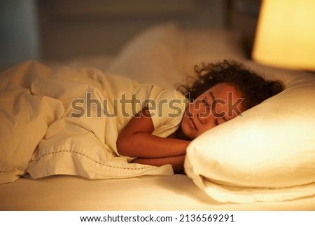 I like moms bed the best. A cute little girl fast asleep in a double bed. Royalty-Free Stock Photo #2136569291