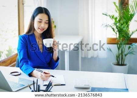 Manager, entrepreneur, female employee sitting and drinking coffee expressing a smiling face while taking a break from hard work.