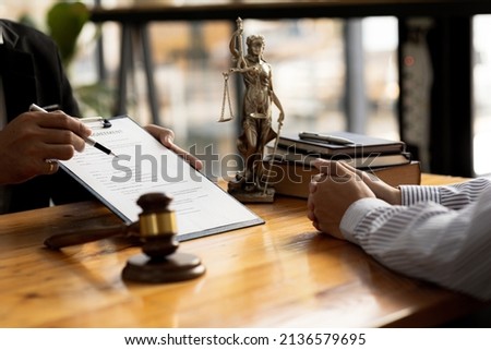 The lawyer explains the contract before allowing the client to sign the lawsuit admitting that the defendant is a business partner who has opened a company and has cheated. Asset embezzlement concept. Royalty-Free Stock Photo #2136579695