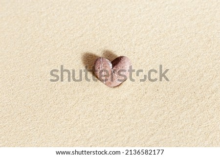 Sea stone form heart pale pink colored on natural fine sand background. Natural pebble in minimal style, concept of nature, calm, peace, love. View from above and copy space