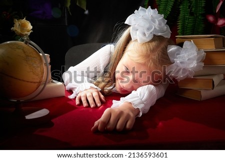 Girl who is elementary school children in uniform having photo shoot in school holiday on September 1 on black background with flowers, books and globe. Holiday of beginning of school in Russia