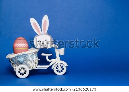 Easter bunny and easter egg on the toy bicycle with blue background.