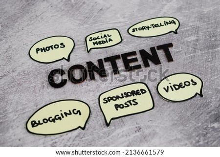content creation and story-telling concept, text surrounded by comic bubble icons with different element of online content from photos and videos to blogs and sponsored posts on concrete background Royalty-Free Stock Photo #2136661579