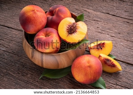 Fresh Yellow Peach fruit in wooden bowl on wooden background, Yellow Peach with slice in wooden basket. Royalty-Free Stock Photo #2136664853