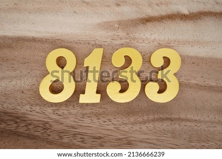 Wooden  numerals 8133 painted in gold on a dark brown and white patterned plank background.