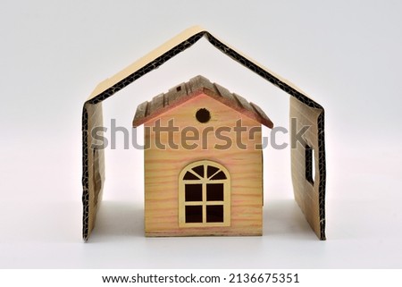 Miniature wooden house protected by an outer cover, isolated on white