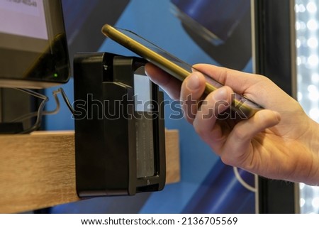 Close-up view of man paying for purchase at micro market (automated unmanned store) using smart phone. Contactless payment theme. Royalty-Free Stock Photo #2136705569