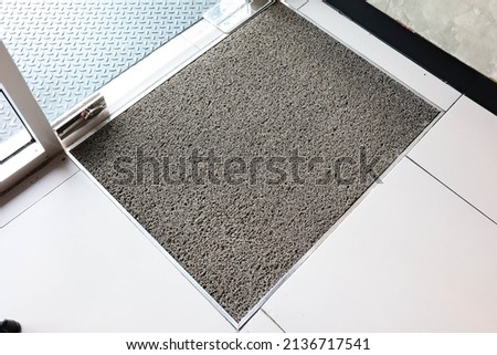 Grey welcome door mat in front of door.