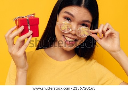 Portrait Asian beautiful young woman wearing diamond glasses small gift box yellow background unaltered
