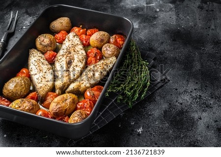 Roasted halibut fish steaks with tomato and potato. Black background. Top view. Copy space.