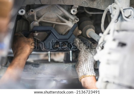 Car mechanic installing engine mount. Royalty-Free Stock Photo #2136723491