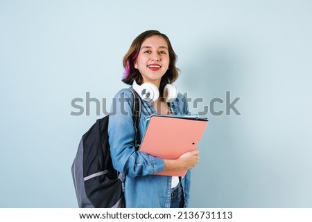Young Hispanic student woman wearing backpack and holding books over isolated blue background