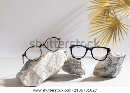 Clear Eyeglasses Glasses with plastic Frame Fashion Vintage Style on gray Background, trendy Still Life Style. Tortoiseshell frame glasses on stones. Optic store advertisement background Royalty-Free Stock Photo #2136731827
