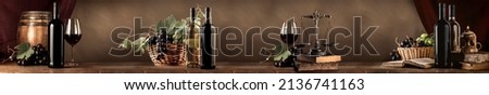 Wine tasting in the wine cellar: red and white bottles of wine, glasses and a panoramic view of the vineyards at sunset
