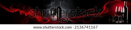 Wine tasting in the wine cellar: red and white bottles of wine, glasses and a panoramic view of the vineyards at sunset Royalty-Free Stock Photo #2136741167