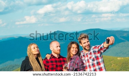 Group of hikers takes photo in nature. Group of friends taking a selfie in the mountains. Young people on camping trip.