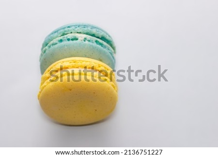 a blue macarons and a yellow one in a woman's hand or on grey surface. tasty delicious desert. colors with meaning. world down syndrome day, march 21. uniqueness of the triplication of the 21st