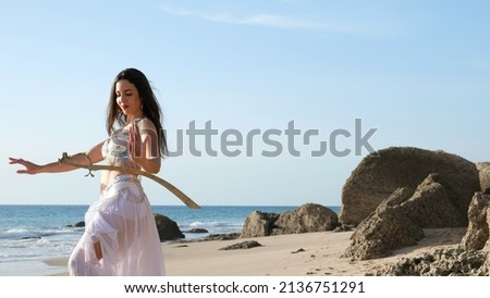 Belly dancer performs on the beach holding her sword