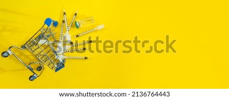 supermarket trolley with syringes and ampoule on yellow panorama background