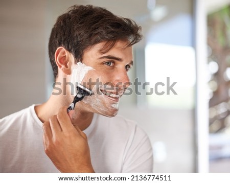 Enjoying his morning routine. Cropped shot of a young man shaving his facial hair with a disposable blade. Royalty-Free Stock Photo #2136774511