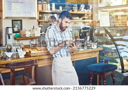 Creating a presence on social media. Shot of a young man using a digital tablet while working in a coffee shop.