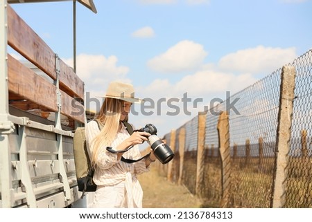Beautiful female tourist with photo camera on safari