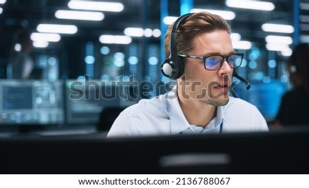 Customer Service Operator at Work in Call Center. Caucasian Call Center Worker Talking with Customer in Modern Office at Night. Worker Speaking on Video Call on Computer Sitting at Table at Office Royalty-Free Stock Photo #2136788067