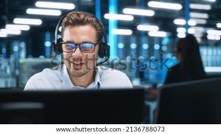 Serious Young Caucasian Man with Headset, Successful Manager of Call Center Sits in Office, Uses Computer, Talking on Video Conference with Client or Employee. Helpline Concept Royalty-Free Stock Photo #2136788073