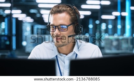 Concentrated Male Customer Support Agent Receptionist wear Headset Consult Online Client Looking at Computer Screen, Helpline Operator Secretary Make Conference Video Call Royalty-Free Stock Photo #2136788085