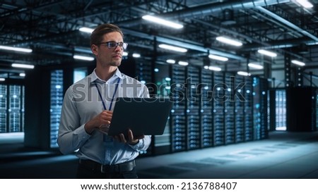 Technology Research Facility: Male Project Manager Standing at the Corridor and Uses Tablet Computer. Engineers or Developers Work on Engine Design and Use Digital Computers Royalty-Free Stock Photo #2136788407