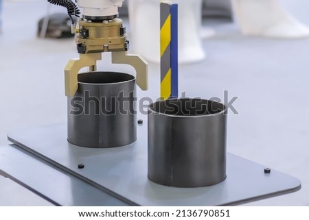 Pick and place industrial robotic clamp arm manipulator moving cylindrical metal workpiece at modern robot exhibition, trade show - close up view. Manufacturing, engineering, ai, technology concept Royalty-Free Stock Photo #2136790851