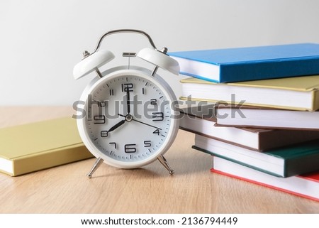 Stack of books and alarm clock on table, closeup