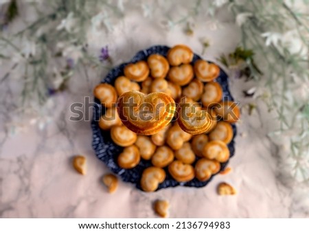 Heart-shaped cookies falling onto a plate seen from above and with the background out of focus