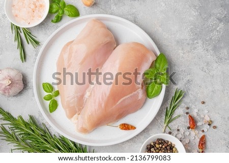 Raw chicken breast or fillet with salt, pepper and fresh herbs on a white plate on a gray background. Healthy food. Top view, copy space Royalty-Free Stock Photo #2136799083