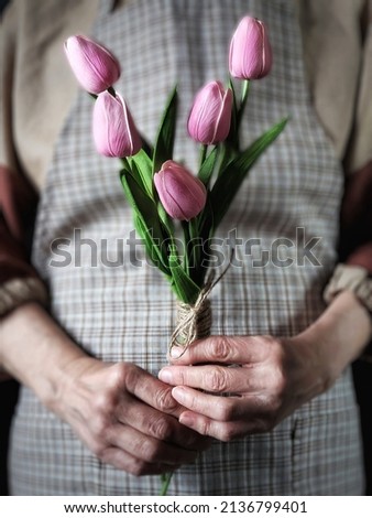 Person holding bouquet of pink tulips in her hands with selective focus. Still life with spring flowers with selective focus. Mother's day