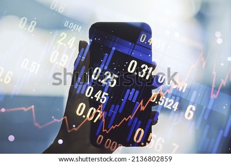 Abstract creative financial graph and hand with phone on background, forex and investment concept. Multiexposure