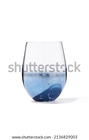 Detailed shot of a transparent glass with a blue mirror coating.  The glass with the effect of the starry sky is isolated on the white background.