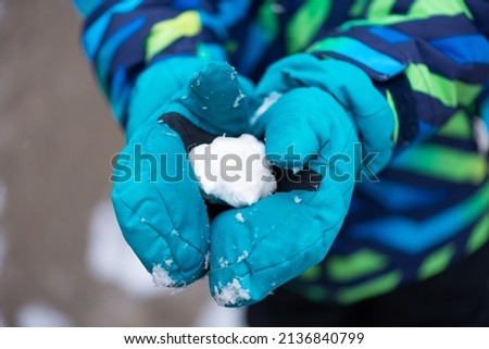 Snowball in the hands of a child close-up