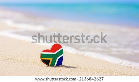 Flag of South Africa in the shape of a heart on a sandy beach. The concept of the best vacation in South Africa. Royalty-Free Stock Photo #2136842627