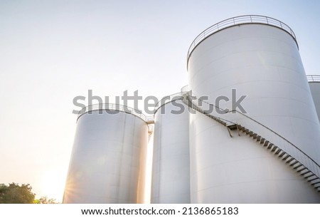 Curved stairway of base oil storage tank in the petroleum factory with blue sky. Industrial petroleum plant. Base oil for automotive engine oil and industrial oil application. Royalty-Free Stock Photo #2136865183