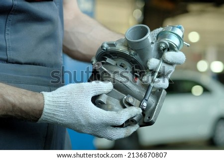 Repair and maintenance of the car. A new turbocharger is in the hands of an auto mechanic. Inspection of the spare part for compliance and integrity. Royalty-Free Stock Photo #2136870807