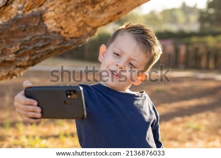 Boy taking selfie picture playing posing and enjoying in the park on a beautiful sunny day