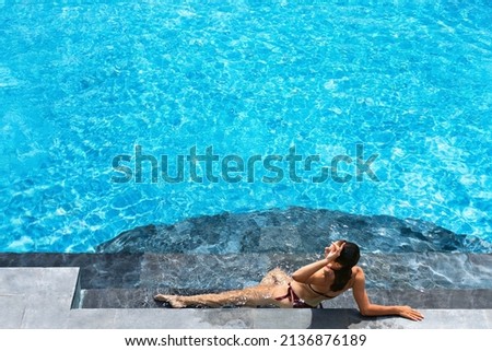 Young beautiful woman on summer beach holiday relaxing in luxury spa hotel in swimming pool with tropical jungle scenic view. Healthy lifestyle, family travel background.