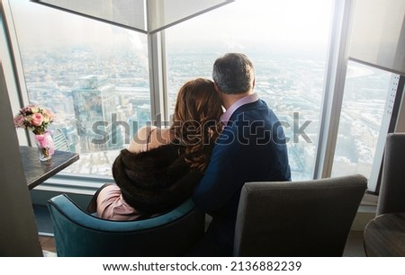 Loving married couple. Wedding anniversary. A man and a woman embracing look into the distance at a beautiful cityscape. The concept of love, family support and a positive future. Royalty-Free Stock Photo #2136882239