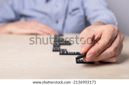 Man laying out dominoes on table. Strategy, business plan drawing up, paving way, planning concept. Hands closeup. Path to development and success. High quality photo