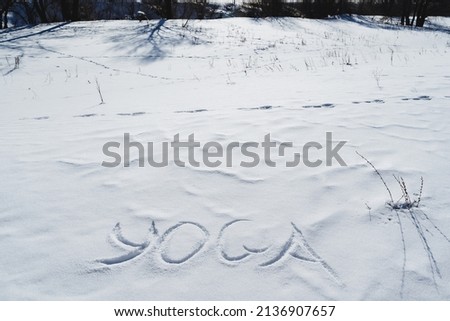 Yoga letters are written on the snow in winter in the cold season. Silence in the text of yogic symbols, a sunny day. High quality photo