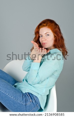 Business portrait of beautiful young woman with red curly hair and blue eyes against gray background. Lifestyle. 